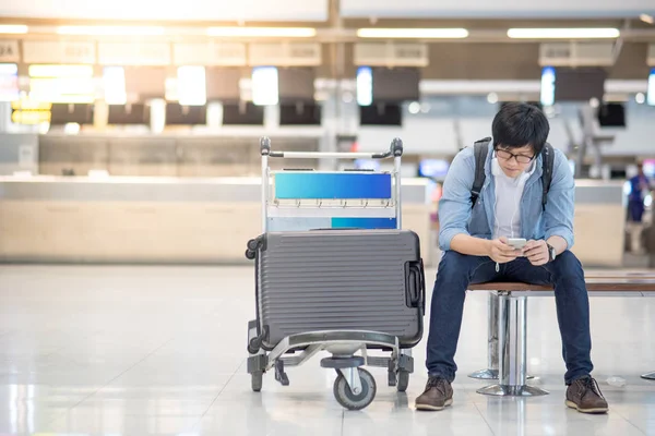 Havaalanı check-in için bekleyen genç Asyalı adam
