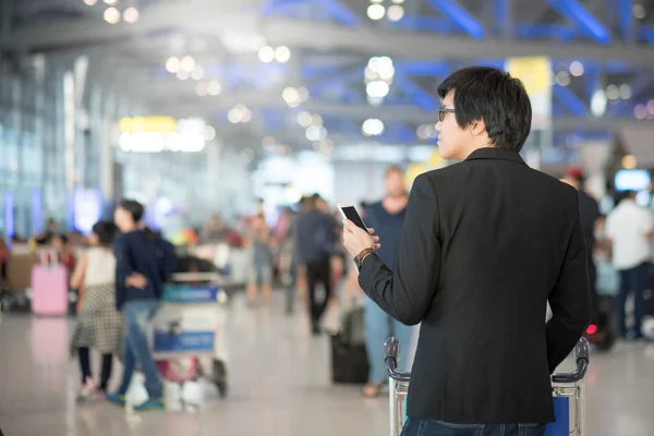Asijský mladík pomocí smartphone v letištní terminál — Stock fotografie