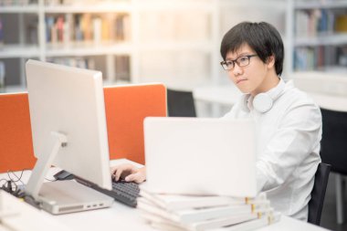 Genç Asyalı adam üniversite öğrencisi bilgisayar kullanarak