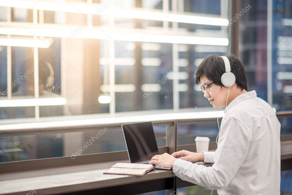 Young Asian man listening to music while working