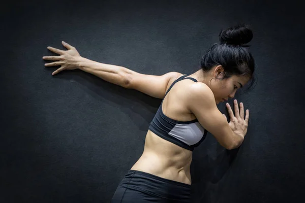 Genç Asyalı kadın siyah duvara kol germe — Stok fotoğraf