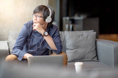 dizüstü bilgisayar ile kanepede oturan genç Asyalı adam