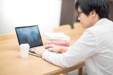 Genç Asyalı adam Üniversitesi Öğrenci Kitaplığı'nda çalışma