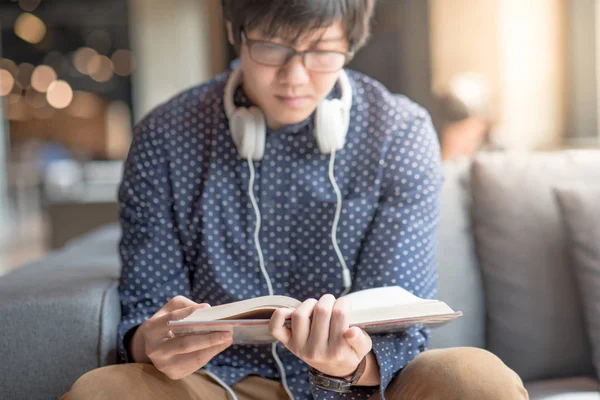 Jeune homme étudiant universitaire livre de lecture sur canapé — Photo