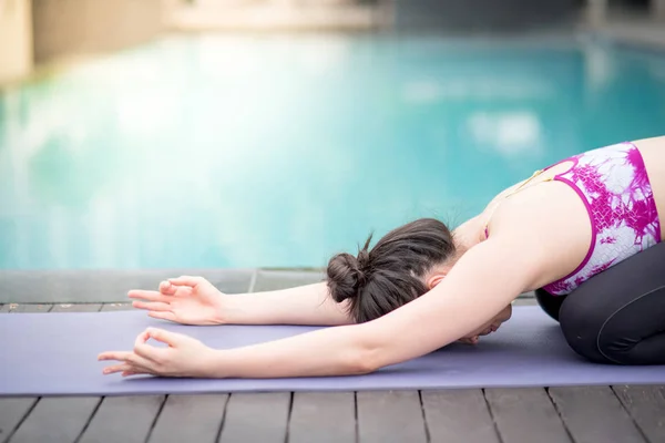 Mujer asiática joven haciendo ejercicio de yoga cerca de la piscina — Foto de Stock