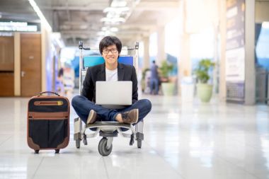 Genç Asyalı adam arabası Havaalanı terminal üzerinde çalışıyor