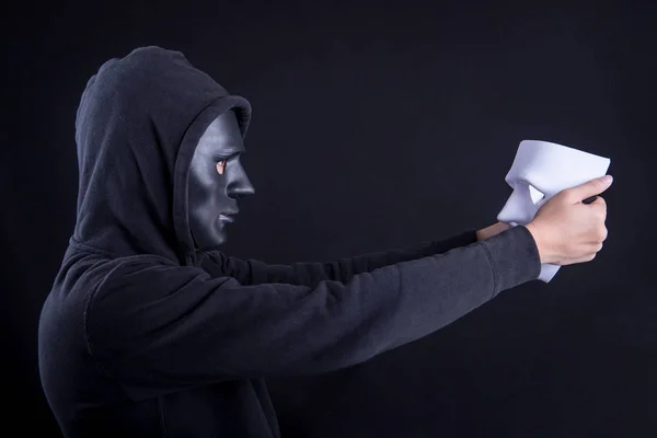 Mysteriöser Mann mit schwarzer Maske, der eine weiße Maske hält und auf sie blickt. Anonyme soziale Maskierung oder Halloween-Konzept. — Stockbild Mysteriöser Mann mit weißer Maske — Stockfoto