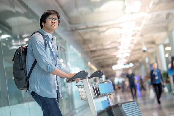 Joven asiático hombre caminando con carro en aeropuerto terminal — Foto de Stock