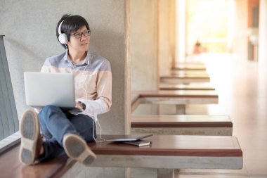 Üniversitede dizüstü bilgisayar kullanan genç Asyalı öğrenci adam