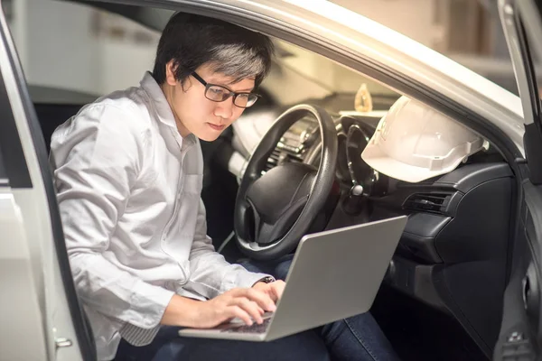 Joven ingeniero asiático o arquitecto que trabaja con el ordenador portátil en su coche — Foto de Stock