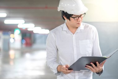 Genç Asyalı dosyaları inşaat alanında tutan mühendisi