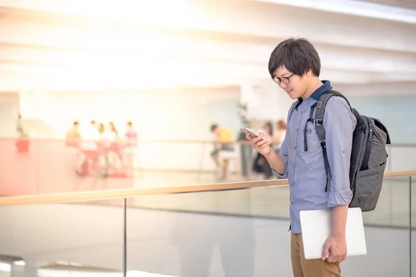 Jonge Aziatische man met behulp van smartphone in winkelcentrum — Stockfoto