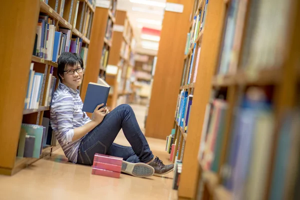 Ung asiatisk man universitet student läsebok i biblioteket — Stockfoto