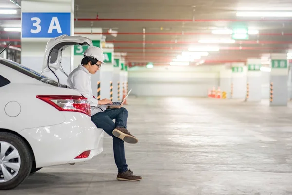 Joven ingeniero asiático trabajando con portátil en el maletero del coche — Foto de Stock