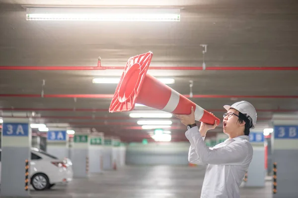 Joven ingeniero asiático gritando a través de cono de seguridad de tráfico en Parki — Foto de Stock