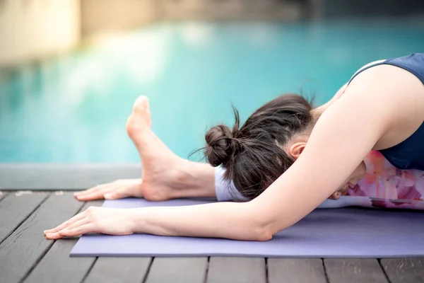 Mujer asiática joven haciendo ejercicio de yoga cerca de la piscina — Foto de Stock