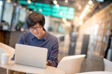  Genç Asyalı adam kafede dizüstü bilgisayar ile çalışma