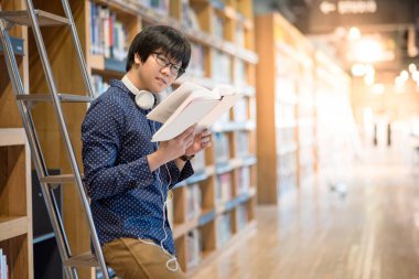 Genç Asyalı adam Üniversitesi Öğrenci okuma kitabı Kitaplığı'nda