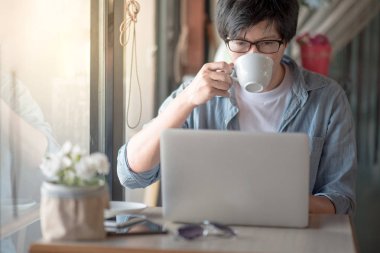 Kahve süre içinde dizüstü bilgisayar kullanan genç Asyalı adam