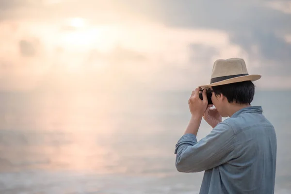 Młody człowiek podróżnik robienia zdjęć zachodu słońca w tropikalnej plaży — Zdjęcie stockowe