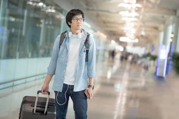 Young Asian man with suitcase luggage in airport terminal