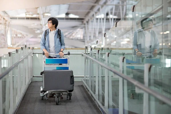 Asijský mladík chůzi s vozíkem v letištní terminál — Stock fotografie