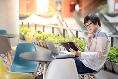 Genç Asyalı öğrenci adam okuma kitap kolej Binası