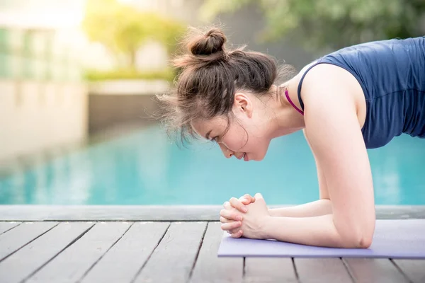 Mujer asiática joven haciendo ejercicio de yoga cerca de la piscina — Foto de Stock