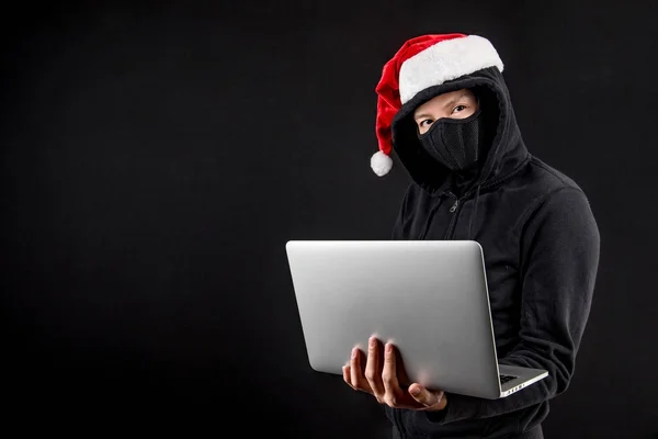 Mysteriöse männliche Weihnachtsmann Hacker hält Laptop-Computer, anonymer Mann auf schwarzem Hintergrund, Ransomware-Cyber-Angriff und Internet-Sicherheit an Weihnachten Konzepte — Stockbild Mysteriöser männlicher Weihnachtsmann-Hacker hält Laptop in der Hand — Stockfoto
