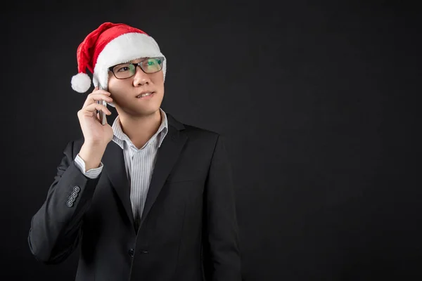 Junger asiatischer Geschäftsmann mit Weihnachtsmütze mit Smartphone — Stockfoto