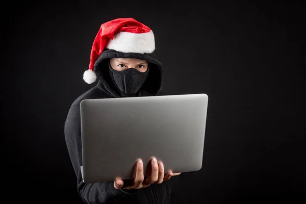 dizüstü bilgisayar tutan gizemli erkek santa bir hacker