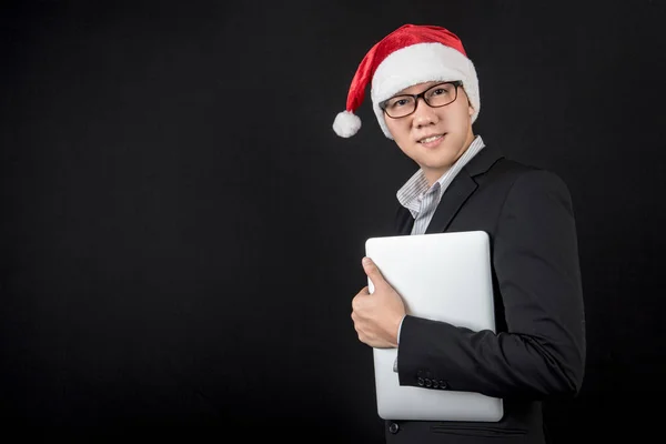 Junger asiatischer Geschäftsmann mit Weihnachtsmütze und Laptop — Stockfoto