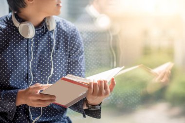 Genç Asyalı adam kitaplığındaki kitap okumak