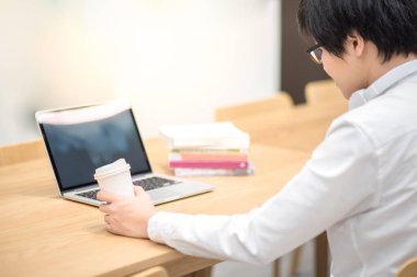 Kahve fincanı çalışırken tutan genç Asyalı adam