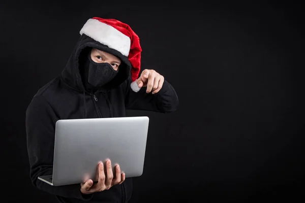 Mysteriöse männliche Weihnachtsmann Hacker hält Laptop-Computer, anonymer Mann auf schwarzem Hintergrund, Ransomware-Cyber-Angriff und Internet-Sicherheit an Weihnachten Konzepte — Stockbild Mysteriöser männlicher Weihnachtsmann-Hacker hält Laptop in der Hand — Stockfoto