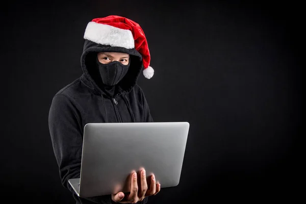 dizüstü bilgisayar tutan gizemli erkek santa bir hacker