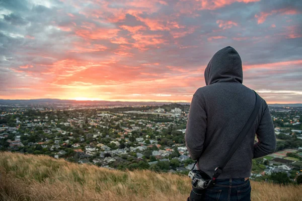 Człowiek sobie z kapturem oglądać wschód słońca nad Auckland city — Zdjęcie stockowe