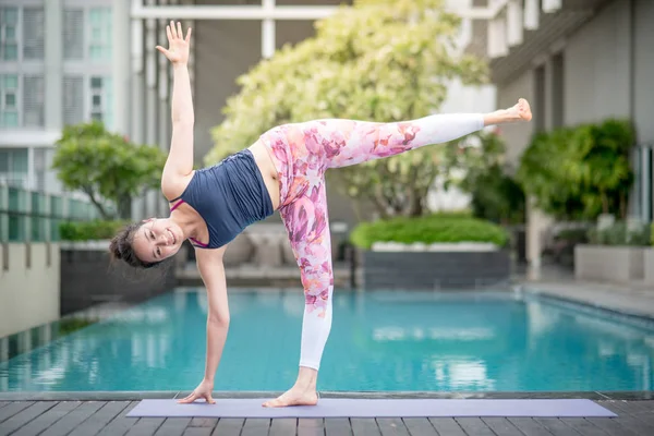 Yüzme Havuzu yanında Yoga egzersiz yaparak genç Asyalı kadın — Stok fotoğraf