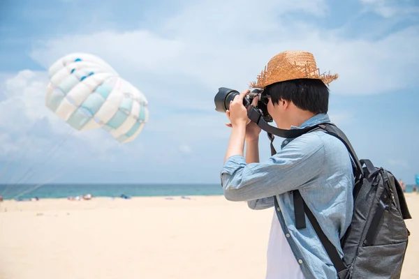Muž fotograf se fotografie parasailing na pláži — Stock fotografie