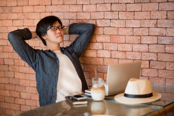 Young Asian man in relax posing while working in cafe