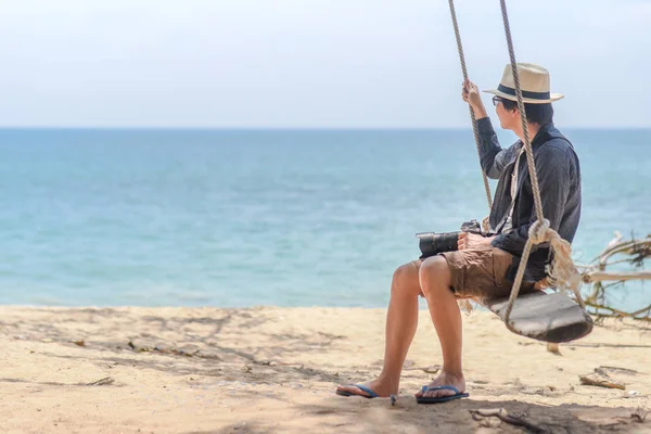 Young Asian photographer man on swing at the beach — Stock Photo, Image