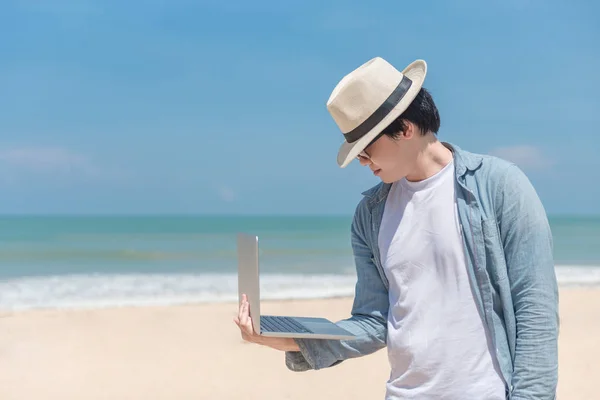 Fiatal ázsiai férfi laptop tartja a strandon — Stock Fotó