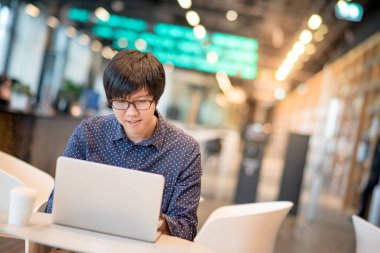  Genç Asyalı adam kafede dizüstü bilgisayar ile çalışma