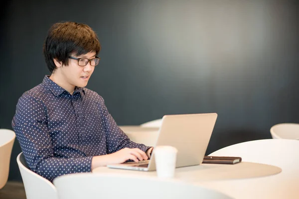 Jovem homem asiático trabalhando com laptop no café — Fotografia de Stock