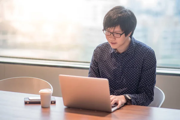 Jovem homem asiático trabalhando com computador portátil no escritório — Fotografia de Stock