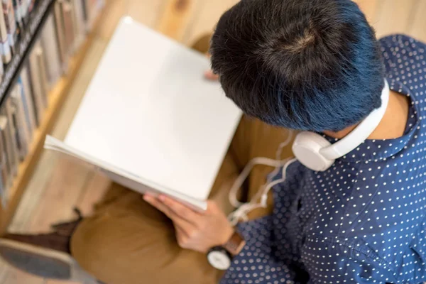 Joven asiático hombre universitario estudiante lectura libro en biblioteca — Foto de Stock