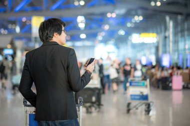 Genç Asyalı adam akıllı telefon Havaalanı terminal kullanarak