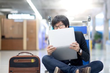 Genç Asyalı adam arabası Havaalanı terminal içinde laptop ile