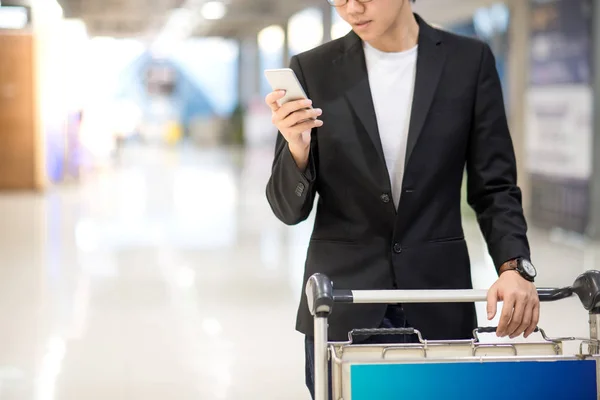Joven asiático hombre usando smartphone en aeropuerto terminal — Foto de Stock