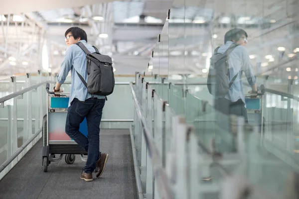 Ung asiatisk man promenader med vagnen i flygplatsterminalen — Stockfoto